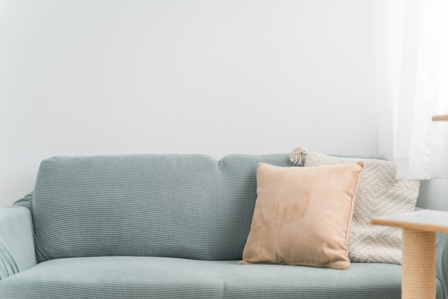 パステルブルーのソファと淡いオレンジのクッション