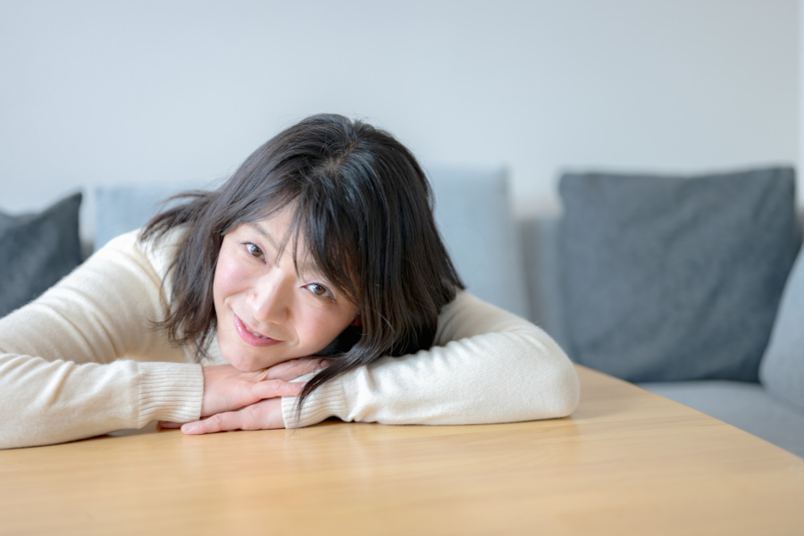 テーブルの上に笑顔で突っ伏す女性