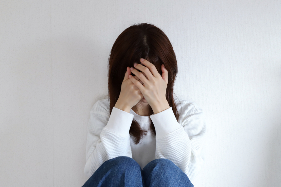 薄暗い部屋。顔を隠し、うつむく女性。