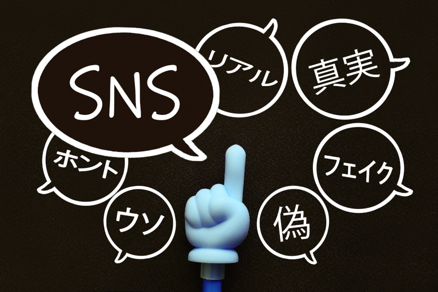 人差し指を建てた手のオブジェと、SNS、リアル、フェイクなどの吹き出し。