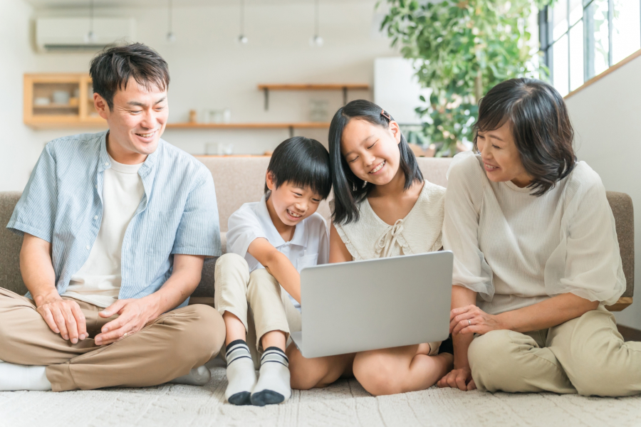 部屋の床に座ってPCをのぞき込む家族4人