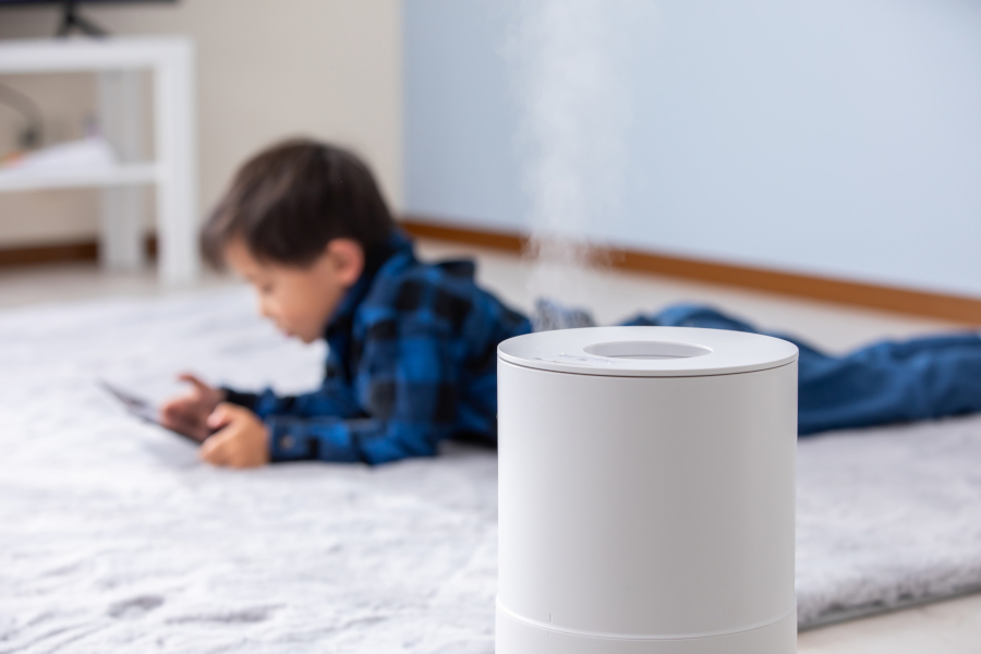 加湿器の向こうで寝転がってゲームする子ども