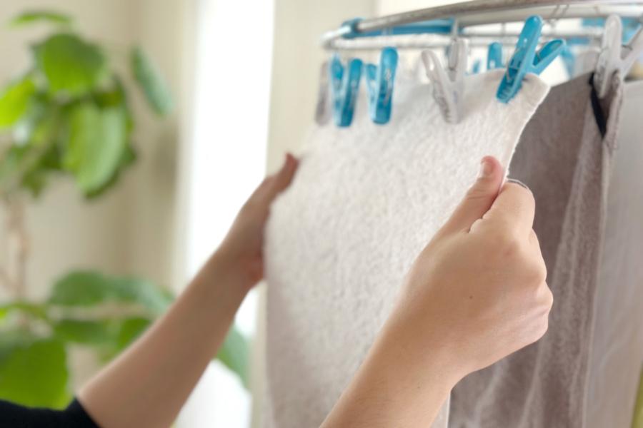 室内で洗濯物を干す女性の手