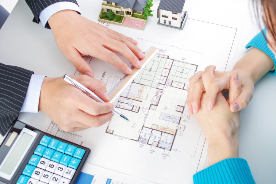 打ち合わせ中に図面に線を引く設計士と女性の手元