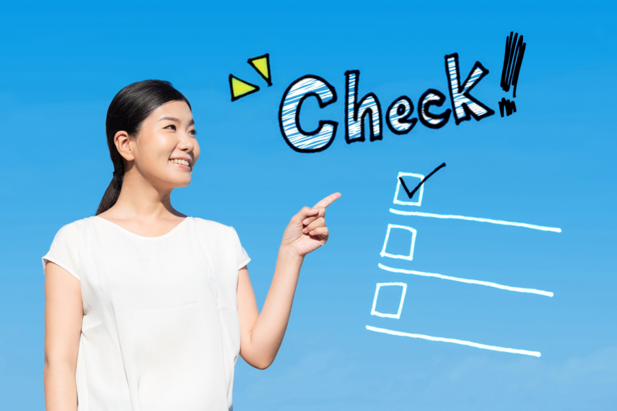 青空のようなブルーの拝啓と手書きのチェックリストを指す女性